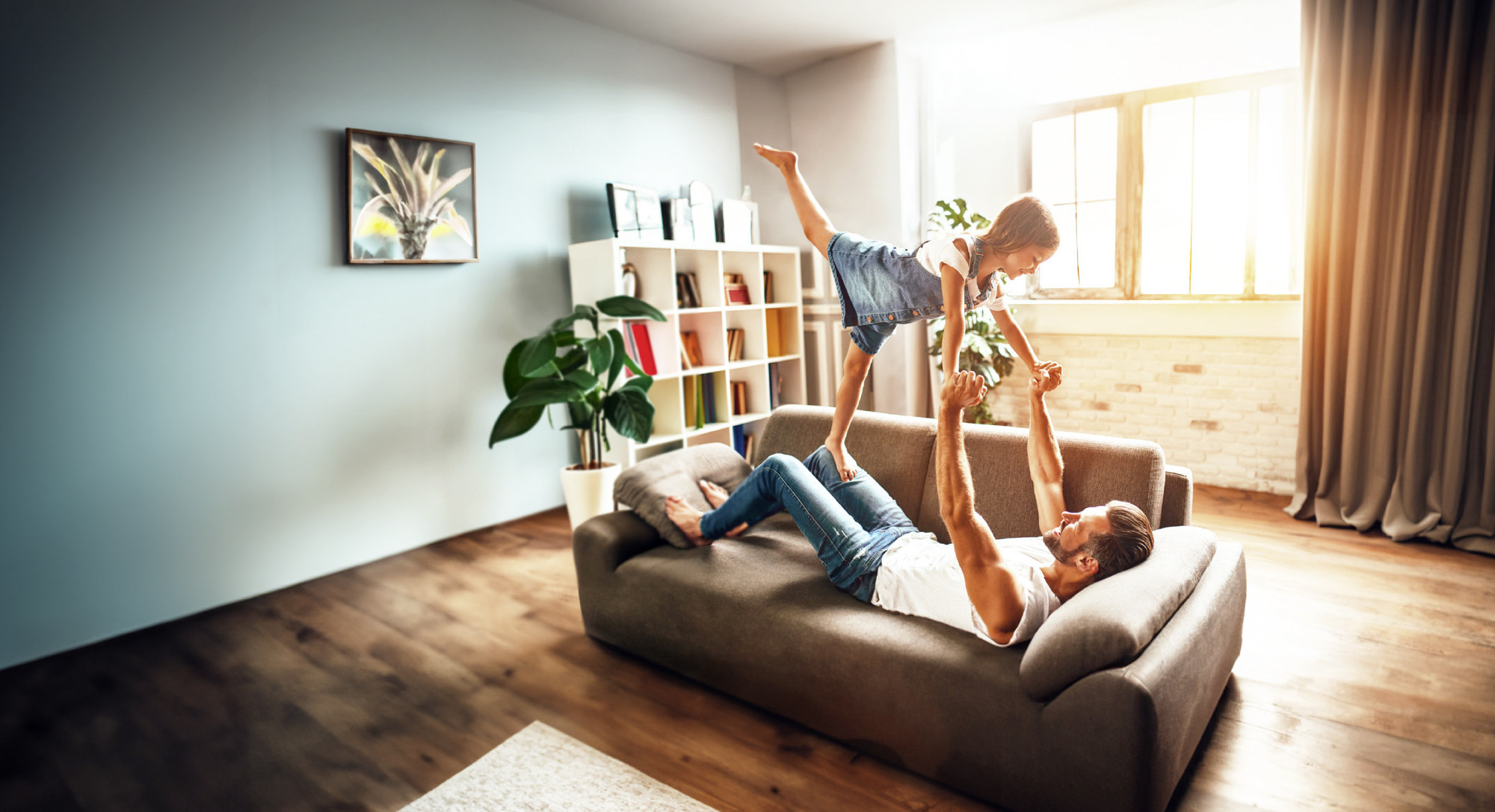 Vater und Tochter spielen im Wohnzimmer auf der Couch